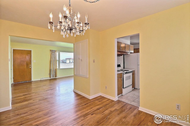 interior space featuring light wood-style floors, baseboards, an inviting chandelier, and electric range