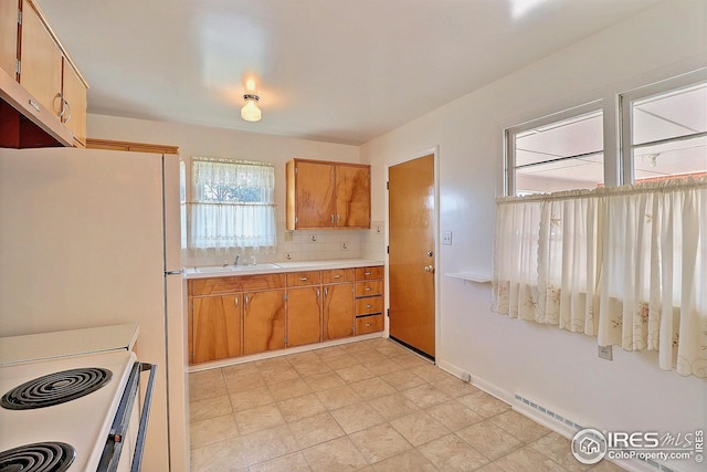 kitchen featuring a sink, white appliances, light countertops, and brown cabinets