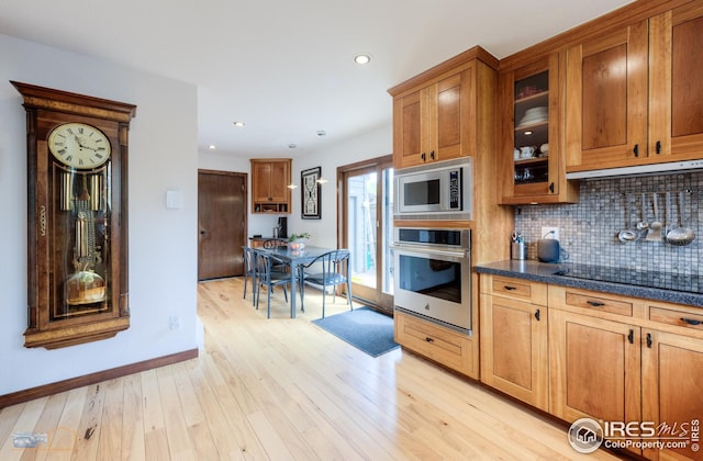 kitchen with brown cabinets, light wood-style floors, stainless steel appliances, backsplash, and recessed lighting