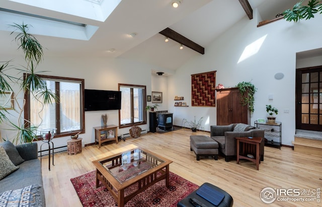 living room with light wood-style floors, a skylight, beamed ceiling, baseboard heating, and high vaulted ceiling