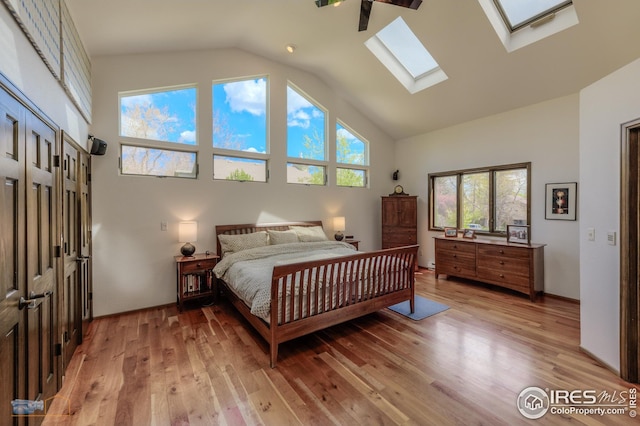 bedroom featuring a skylight, light wood-style flooring, and high vaulted ceiling