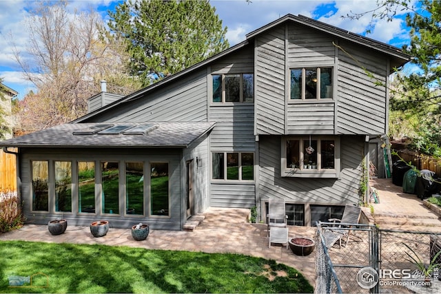 back of house with fence, a lawn, a chimney, and a patio