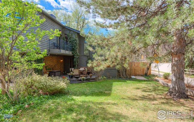 view of yard with fence, a patio, and a balcony