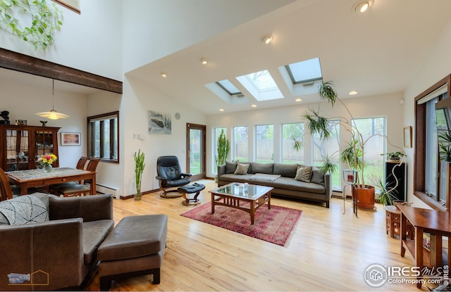 living room featuring a skylight, a baseboard heating unit, a towering ceiling, light wood finished floors, and recessed lighting