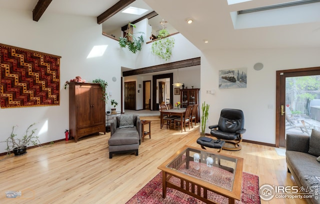 living area with a skylight, wood finished floors, and high vaulted ceiling