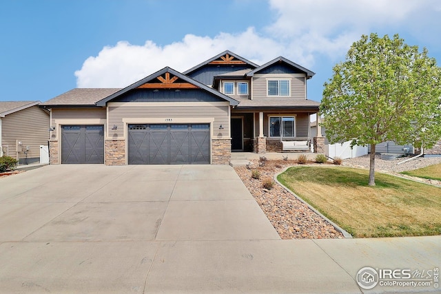 craftsman-style house featuring driveway, stone siding, a front yard, a porch, and a garage