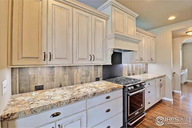 kitchen with tasteful backsplash, light wood-style floors, baseboards, cream cabinetry, and gas stove