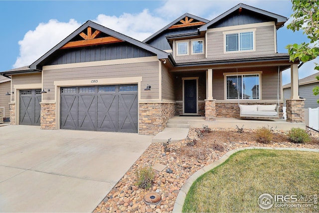 craftsman-style home featuring a porch, driveway, an attached garage, and stone siding