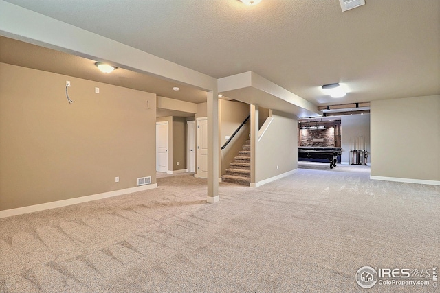 finished basement with baseboards, visible vents, stairs, and carpet flooring