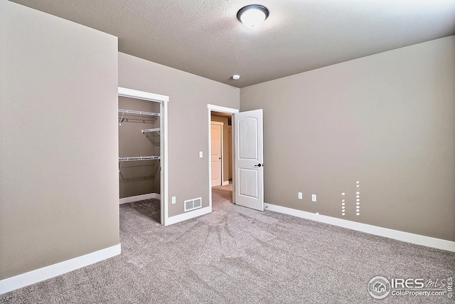 unfurnished bedroom with a closet, visible vents, baseboards, carpet floors, and a spacious closet
