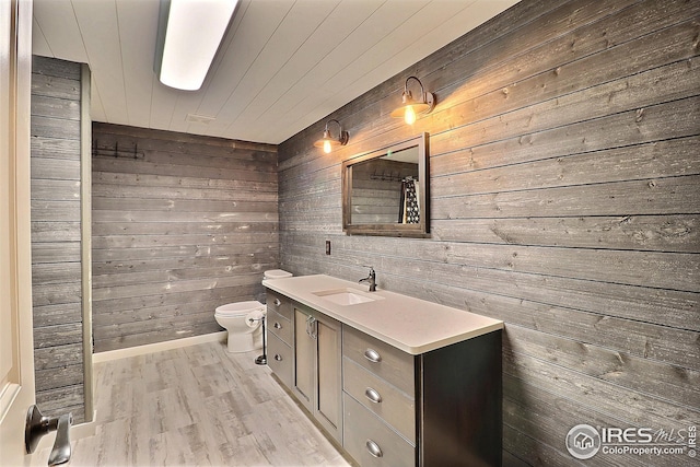 full bath with wood finished floors, wood ceiling, wood walls, toilet, and vanity