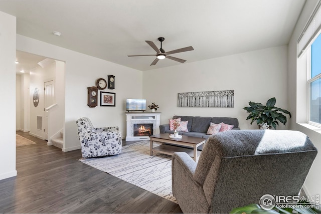 living room featuring a fireplace, wood finished floors, a ceiling fan, and baseboards