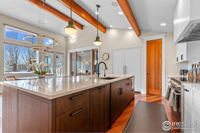 1533 Old Tale Rd, Boulder, CO 80303 - kitchen with wall chimney exhaust hood, stainless steel range, a center island with sink, wood finished floors, and light countertops