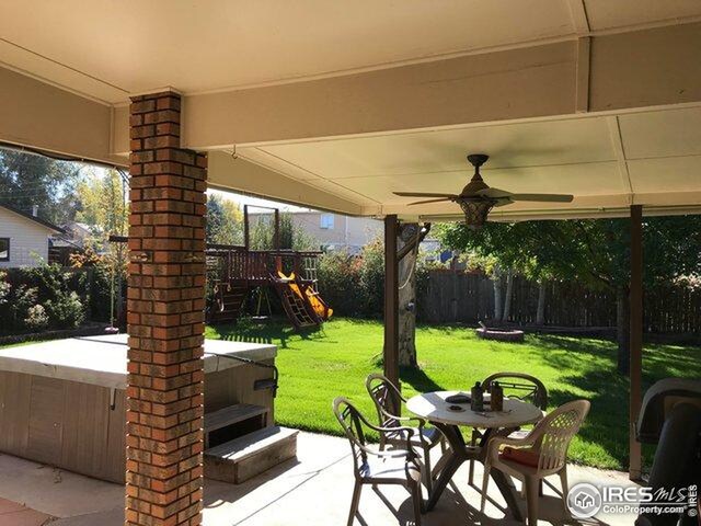 view of patio with a fenced backyard, a hot tub, outdoor dining area, a ceiling fan, and a playground