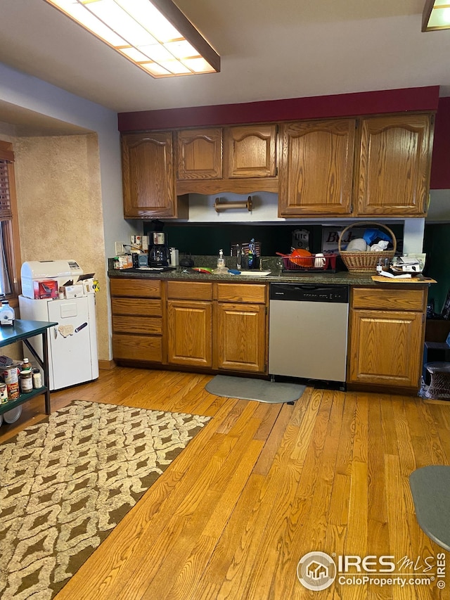 kitchen with stainless steel dishwasher, a sink, brown cabinets, and light wood-style floors