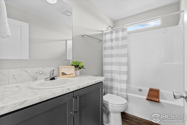 full bathroom featuring shower / bath combo, a textured ceiling, toilet, wood finished floors, and vanity