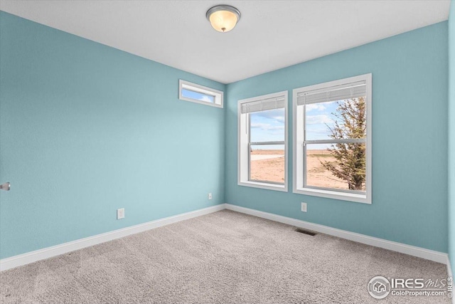 carpeted spare room with visible vents and baseboards