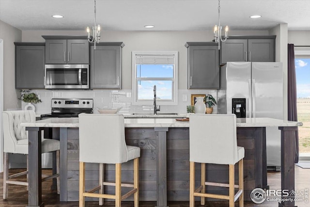 kitchen featuring gray cabinetry, a notable chandelier, a sink, and stainless steel appliances