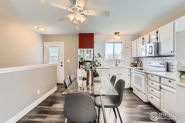 kitchen featuring white appliances, backsplash, dark wood finished floors, and a sink