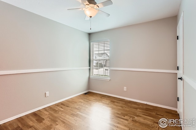 spare room featuring a ceiling fan, wood finished floors, and baseboards