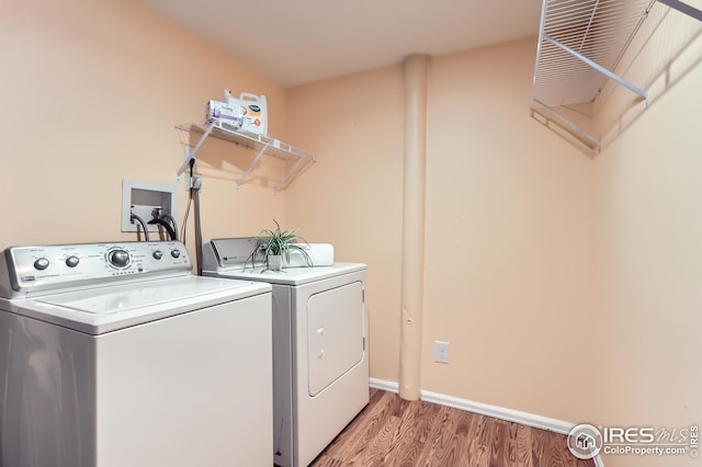 laundry area featuring washer and clothes dryer, baseboards, laundry area, and light wood-style flooring