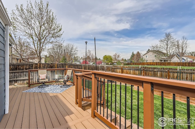 wooden deck with a residential view, a yard, and a fenced backyard