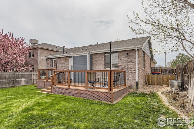 back of property featuring a lawn, a wooden deck, brick siding, and a fenced backyard