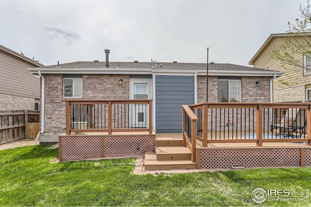 rear view of property featuring fence, a yard, brick siding, and a wooden deck