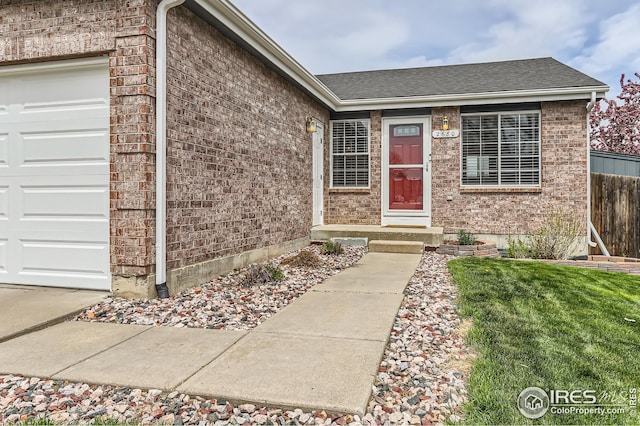doorway to property featuring fence, roof with shingles, a garage, and brick siding