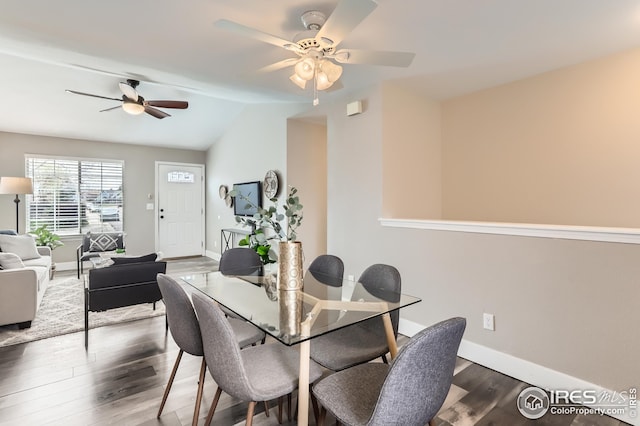 dining space featuring wood finished floors, a ceiling fan, vaulted ceiling, and baseboards