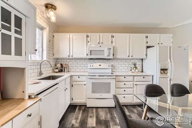 kitchen featuring white cabinets, a sink, light countertops, dark wood finished floors, and white appliances