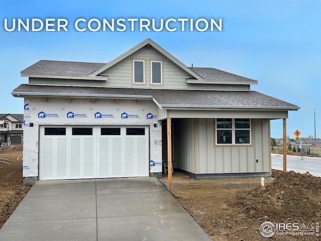 view of front of home featuring roof with shingles, board and batten siding, an attached garage, and driveway