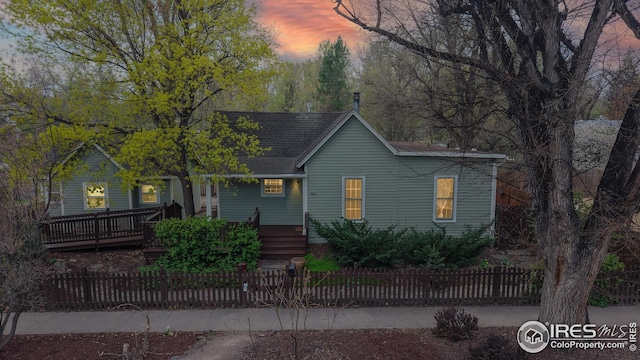 ranch-style home featuring a fenced front yard and roof with shingles