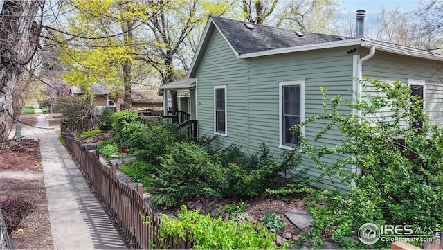 view of side of property featuring a shingled roof and fence