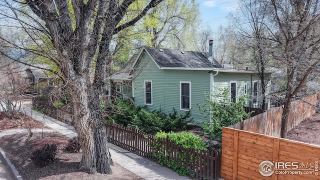 view of side of home with fence and a shingled roof