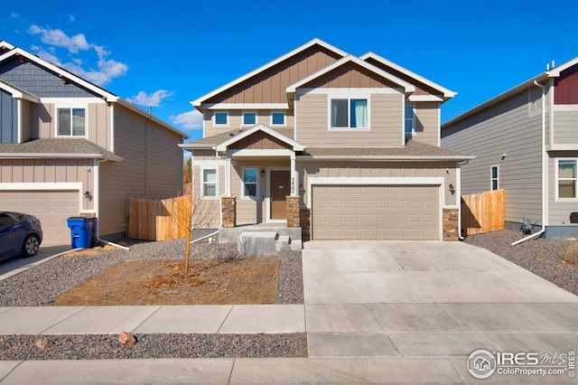 craftsman house with driveway, stone siding, board and batten siding, an attached garage, and fence