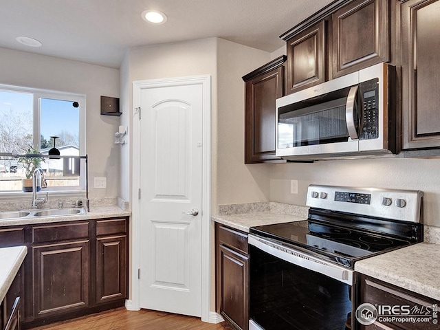 kitchen featuring dark brown cabinets, appliances with stainless steel finishes, light countertops, and a sink