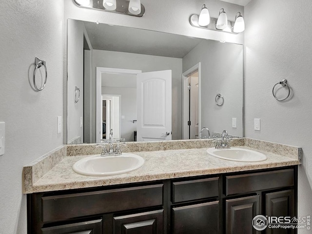 bathroom with double vanity, a sink, and a textured wall