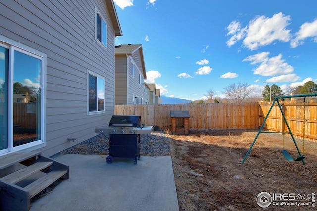 view of patio / terrace with area for grilling, a fenced backyard, and a playground