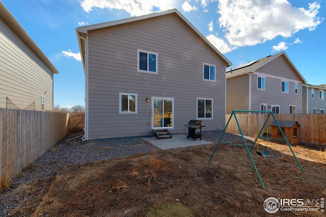 rear view of house with a fenced backyard, a patio area, and a playground