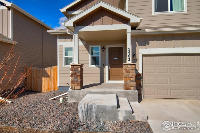 doorway to property featuring fence, board and batten siding, and driveway