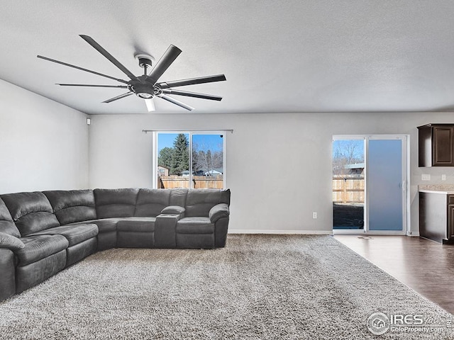 living area with baseboards, wood finished floors, a ceiling fan, and a textured ceiling