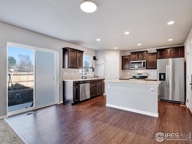 kitchen with appliances with stainless steel finishes, visible vents, light countertops, dark brown cabinetry, and dark wood-style flooring