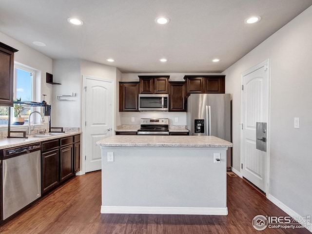 kitchen featuring a sink, appliances with stainless steel finishes, a center island, light countertops, and dark brown cabinets