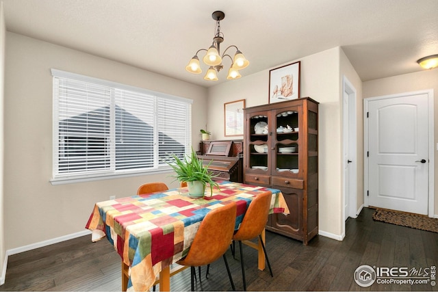 dining area with a notable chandelier, dark wood finished floors, and baseboards
