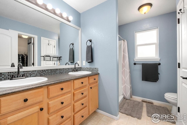 full bath featuring toilet, a shower with curtain, double vanity, and a sink