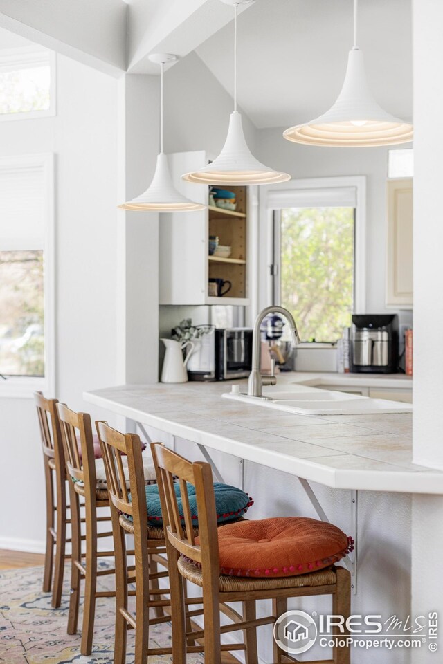 1891 Orchard Ave, Boulder, CO 80304 - kitchen featuring a sink, a breakfast bar, decorative light fixtures, wood finished floors, and open shelves