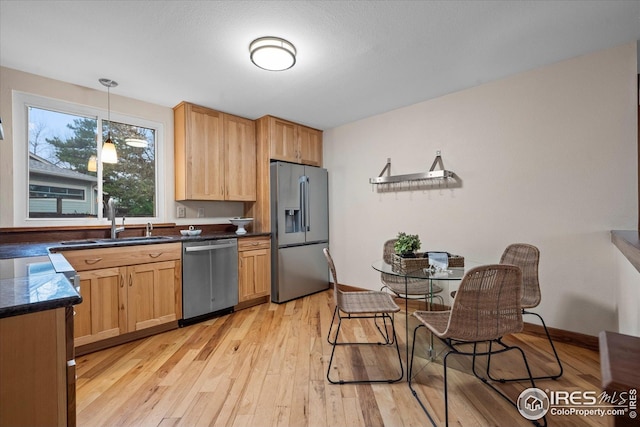 kitchen featuring dark countertops, light wood finished floors, a sink, and stainless steel appliances