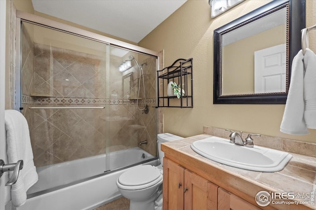 bathroom featuring toilet, enclosed tub / shower combo, and vanity