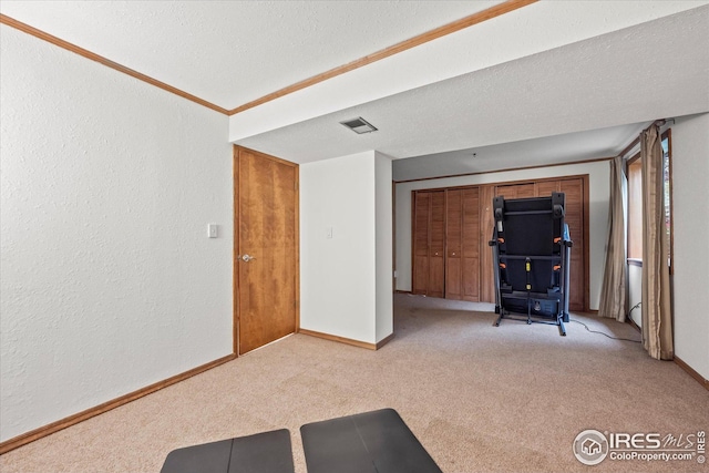 interior space with a textured ceiling, carpet flooring, visible vents, a textured wall, and baseboards